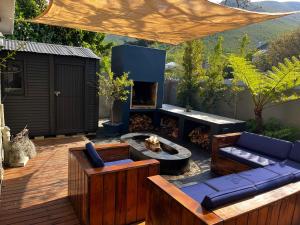 a patio with a fire pit and a couch and chairs at Seven on Flora- Hot Tub, Modern with amazing outside area in Hermanus