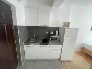 eine kleine Küche mit weißen Schränken und einer Mikrowelle in der Unterkunft Studio Apartman Centar in Zenica