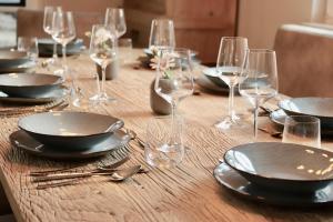 a wooden table with plates and wine glasses on it at HaffSide Usedom in Zirchow