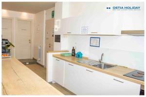 a kitchen with white cabinets and a sink at Ostia Holiday Sunset in Lido di Ostia