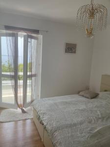 a bedroom with a bed and a window with a chandelier at La grande bellezza in Martinšćica