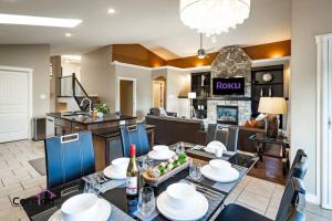 a dining room and living room with a table and chairs at Luxury Retreat, Sleeps 12, AC, Patio, 5 min to YQL in Lethbridge