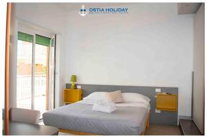 Un dormitorio con una cama y una silla y una ventana. en Ostia Holiday Sunset, en Lido di Ostia