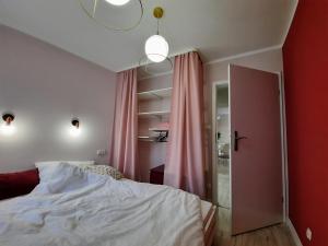 a bedroom with a bed and a pink curtain at Apartament Kwietniewskiego 4 Bytom in Bytom