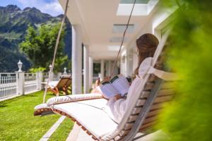 een vrouw die op een veranda zit te schommelen en een boek leest bij B&B Das Land-Palais - PRIVATE Mountain Hideaway in Selva dei Molini