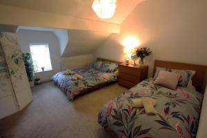 a bedroom with two beds and a lamp and a window at Lymm Village Apartment in Lymm