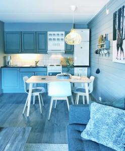 cocina con armarios azules, mesa y sillas en Fjellstova Storehorn Apartments, en Torset