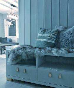a blue couch with a furry cushion and pillows on it at Fjellstova Storehorn Apartments in Torset