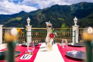uma mesa com uma toalha de mesa vermelha com pratos e copos de vinho em B&B Das Land-Palais - PRIVATE Mountain Hideaway em Selva dei Molini