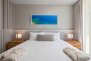 a bedroom with a large white bed with two lamps at Alaia Belize, Autograph Collection in San Pedro