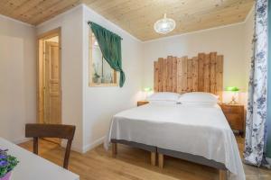 a bedroom with a white bed and a wooden ceiling at B&B Cà Selvetta in Forcola