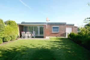 a brick house with chairs on a lawn at Ferienhaus Albatrosstr 36 Ostermann Bungalow 2 in Norddeich
