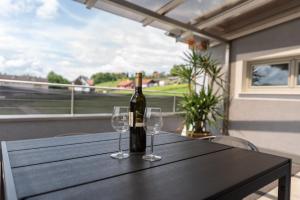 Appartement Gamlitz في غامليتز: زجاجة من النبيذ موضوعة على طاولة مع كأسين