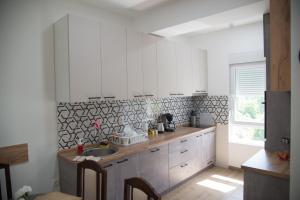 una cocina con armarios blancos y fregadero en ZOJA Apartments #2, en Kavadarci