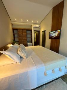 a bedroom with a large white bed with a flat screen tv at Hotel da Pipa in Pipa