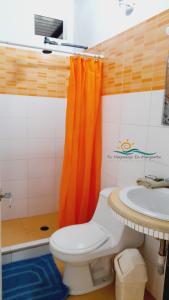 un bagno con servizi igienici e tenda arancione per la doccia. di Casa Vacacional8 Lomas de Guayamury a Loma de Guerra