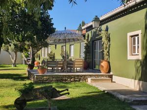 una casa verde con un banco y una sombrilla en Quinta do Pinheiro Hotel Rural - GQL, en Valado dos Frades