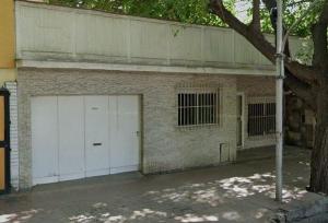 un bâtiment en briques avec deux portes de garage blanches dans l'établissement Central Park Mendoza, à La Cieneguita