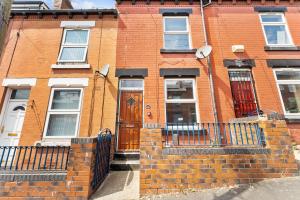 a brick building with a brown door and a fence at Large 4 bed in Leeds - Sleeps 10 - Parking in Leeds