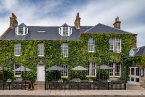 a building covered in ivy with tables and umbrellas at The Bonnie Badger in Gullane