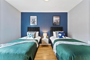 2 camas en una habitación con paredes azules en Large 4 bed in Leeds - Sleeps 10 - Parking, en Leeds