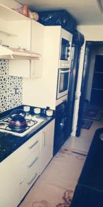 a kitchen with white cabinets and a stove top oven at شقة مجهزة للكراء في فرح السلام الألفة in Casablanca