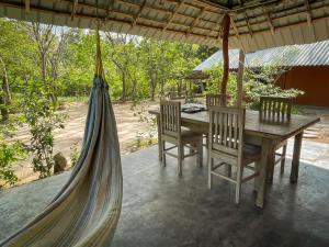 a hammock on a patio with a table and chairs at Sahana Retreat in Buttala
