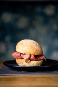 a bacon sandwich on a black plate on a table at The Bonnie Badger in Gullane