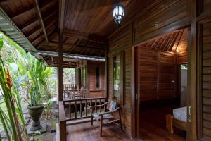eine offene Veranda eines Holzhauses mit einem Bett und Stühlen in der Unterkunft Green Villas Lembongan by ABM in Nusa Lembongan