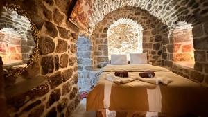 ein Schlafzimmer mit einem Bett in einem Steinzimmer in der Unterkunft Acabey Konuk Evleri in Mardin