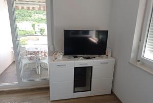 una TV a schermo piatto seduta sopra un armadio bianco di Apartman Nimfa a Igrane