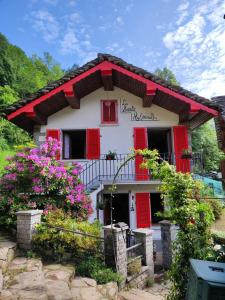 une maison avec des volets rouges et des fleurs devant elle dans l'établissement La baita alpina, à Scopello