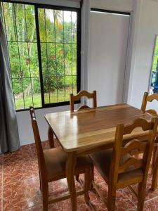 einen Holztisch und Stühle in einem Zimmer mit Fenster in der Unterkunft Casa de campo entera rodeada de naturaleza en Sarapiquí in Heredia