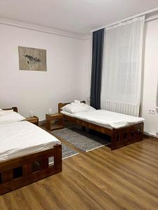 two beds in a room with wooden floors at Pataky Apartmanok in Veszprém