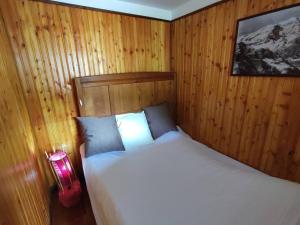 1 dormitorio con 1 cama blanca con paneles de madera en La baita alpina, en Scopello