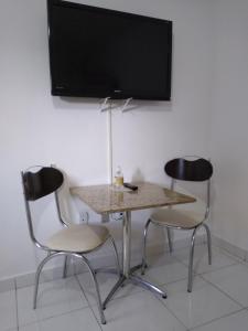 twee stoelen en een tafel met een televisie aan de muur bij Recanto Só Alegria 2 in Serra Negra