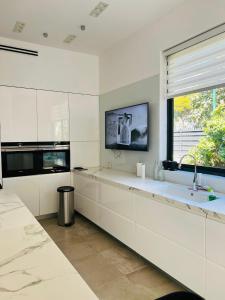 een witte keuken met een wastafel en een raam bij Luxurious house in Ness Tziona in Nes Ẕiyyona
