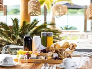 a table with a tray of food and baskets of bread at Bravo Pousada Design in Cabo Frio