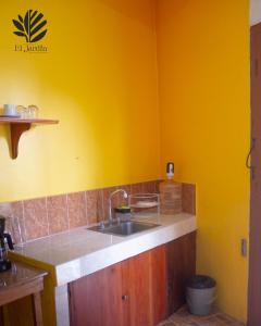 uma cozinha com um lavatório e uma parede amarela em Departamento El Jardín em Xocoyolo