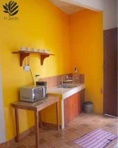 eine Küche mit einer Spüle und einer Mikrowelle auf der Theke in der Unterkunft Departamento El Jardín in Xocoyolo