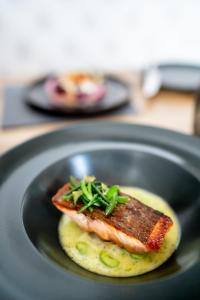 a black plate with a piece of fish on top of food at The Bonnie Badger in Gullane