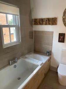 ein Bad mit einer Badewanne, einem WC und einem Fenster in der Unterkunft Dinky cottage in Brightlingsea