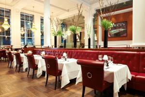 um restaurante com mesas brancas e cadeiras vermelhas em Threadneedles, Autograph Collection em Londres