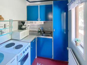 Elle comprend une petite cuisine avec des placards bleus et un évier. dans l'établissement Holiday home HUNVIGAN, à Höllviken