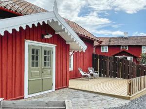 een rood huis met een houten terras met een deur bij Holiday home Mellösa IV in Mellösa