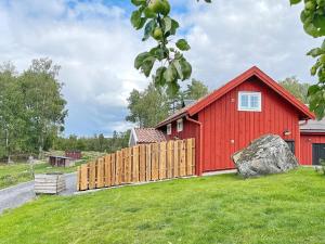 un granero rojo con una valla delante en Holiday home Mellösa IV en Mellösa