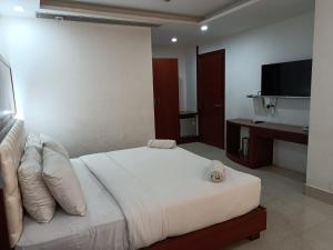 a bedroom with a white bed with a flat screen tv at Hotel Autumn Crocus in Guwahati