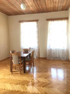 a dining room with a table and chairs and two windows at Guesthouse "KISTAURI" in Telavi