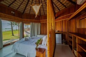 a bedroom with a bed and a large window at BAMBU BLU Lagoon Homes in Itarema