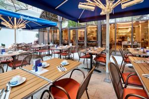 un restaurante con mesas de madera, sillas y sombrillas azules en London Marriott Hotel Regents Park, en Londres